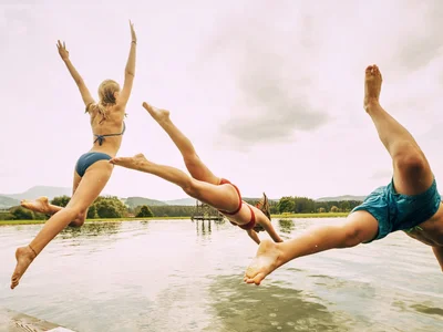 Kinder springen gemeinsam in den See